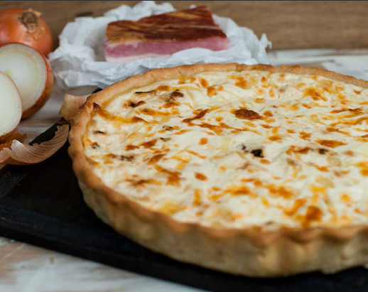 Quiche cortada mostrando massa dourada e recheio cremoso.